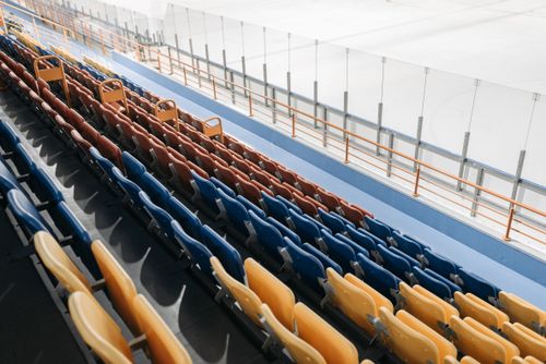 Free An empty stadium with multicolored seats overlooking an ice skating rink. Stock Photo