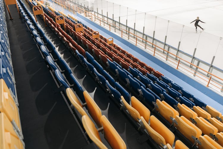 A Person Ice Skating On A Stadium With Empty Bleachers
