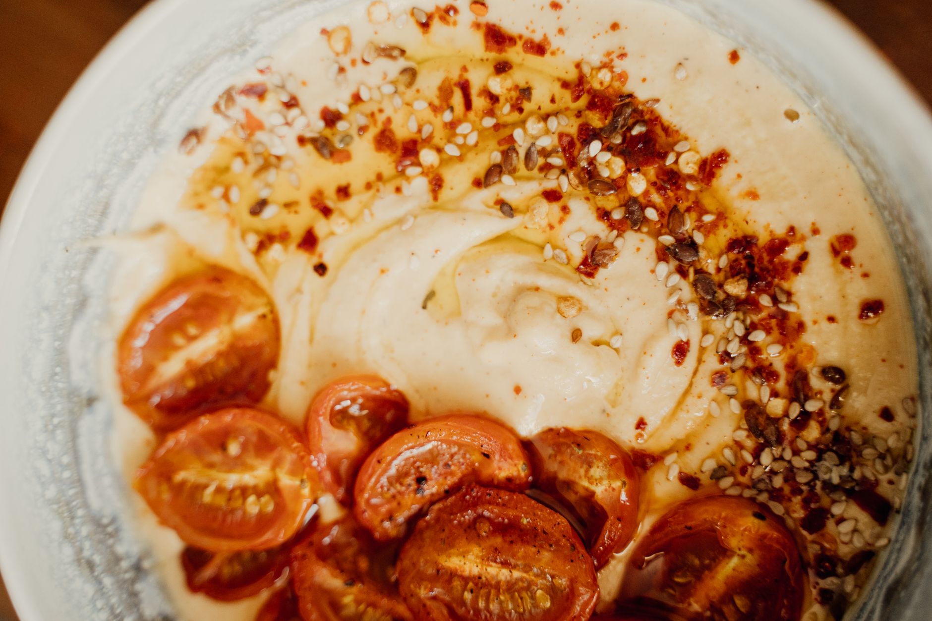 Creamy tahini sauce in bowl beside roasted vegetables