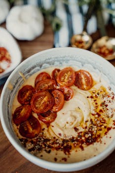 Smooth hummus topped with roasted cherry tomatoes and spices, perfect for a healthy meal.