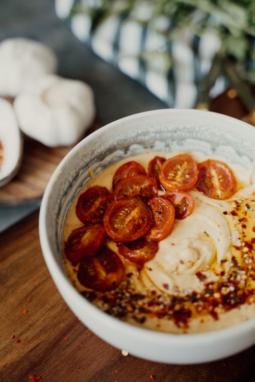 Free Close-up of a bowl of hummus topped with cherry tomatoes and spices, perfect for healthy eating. Stock Photo