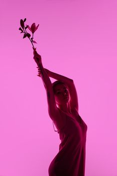 Silhouette of a tattooed woman holding lilies on a pink background. Elegant and artistic.