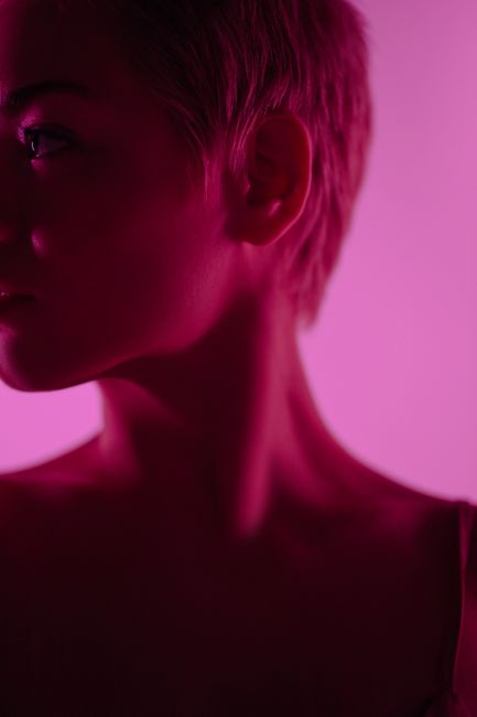 Close-up portrait of a woman with short hair in a neon pink ambiance.