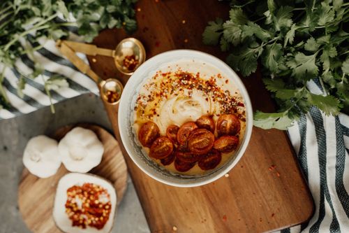Free A delicious bowl of hummus topped with cherry tomatoes and spices, perfect for a vegan snack. Stock Photo