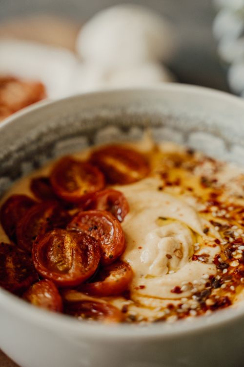 Free Close-up of a delicious hummus bowl topped with cherry tomatoes and spices, showcasing healthy food. Stock Photo