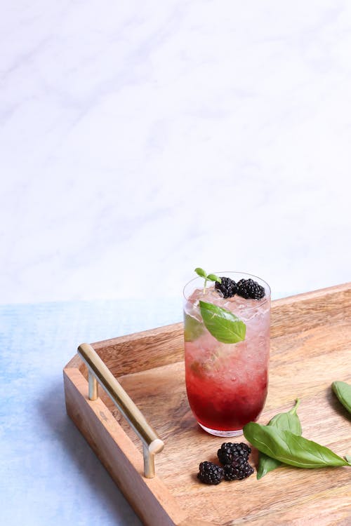 Free Transparent glass of delicious beverage with fresh mint leaves and berries on ice on wooden tray Stock Photo
