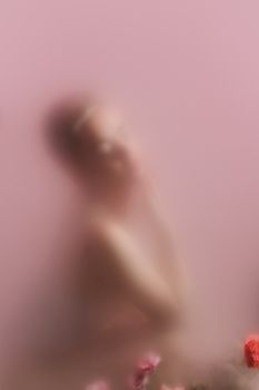 Ethereal blurred portrait with pastel pink background and subtle floral details.