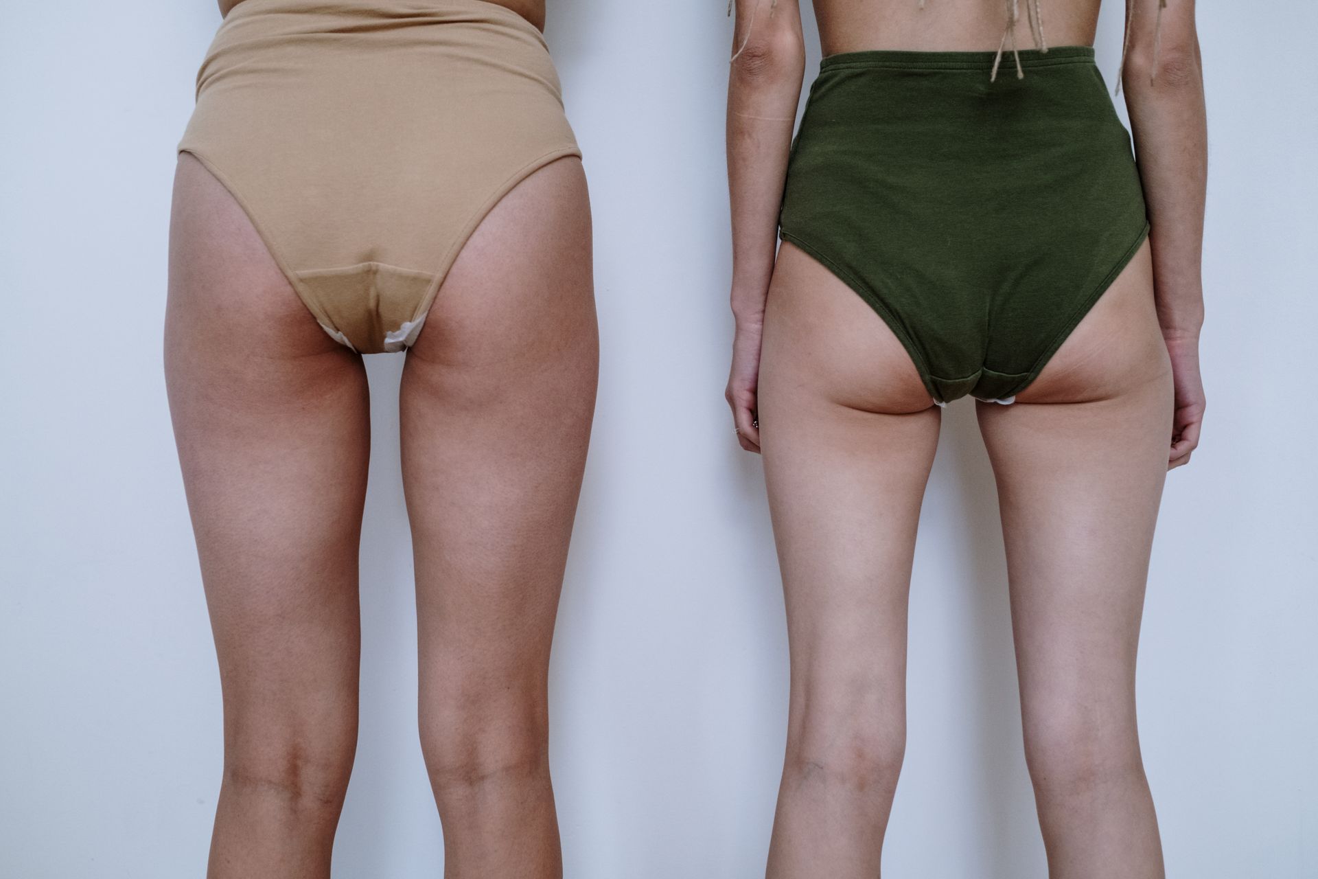 Fashion shot featuring two women standing in high-waisted underwear against a white background.