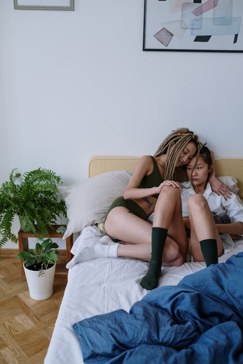 Woman Hugging Her Friend While Sitting on the Bed 