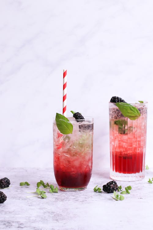Free Different glasses of delicious healthy drinks with mint and fresh blackberries on ice on light background Stock Photo