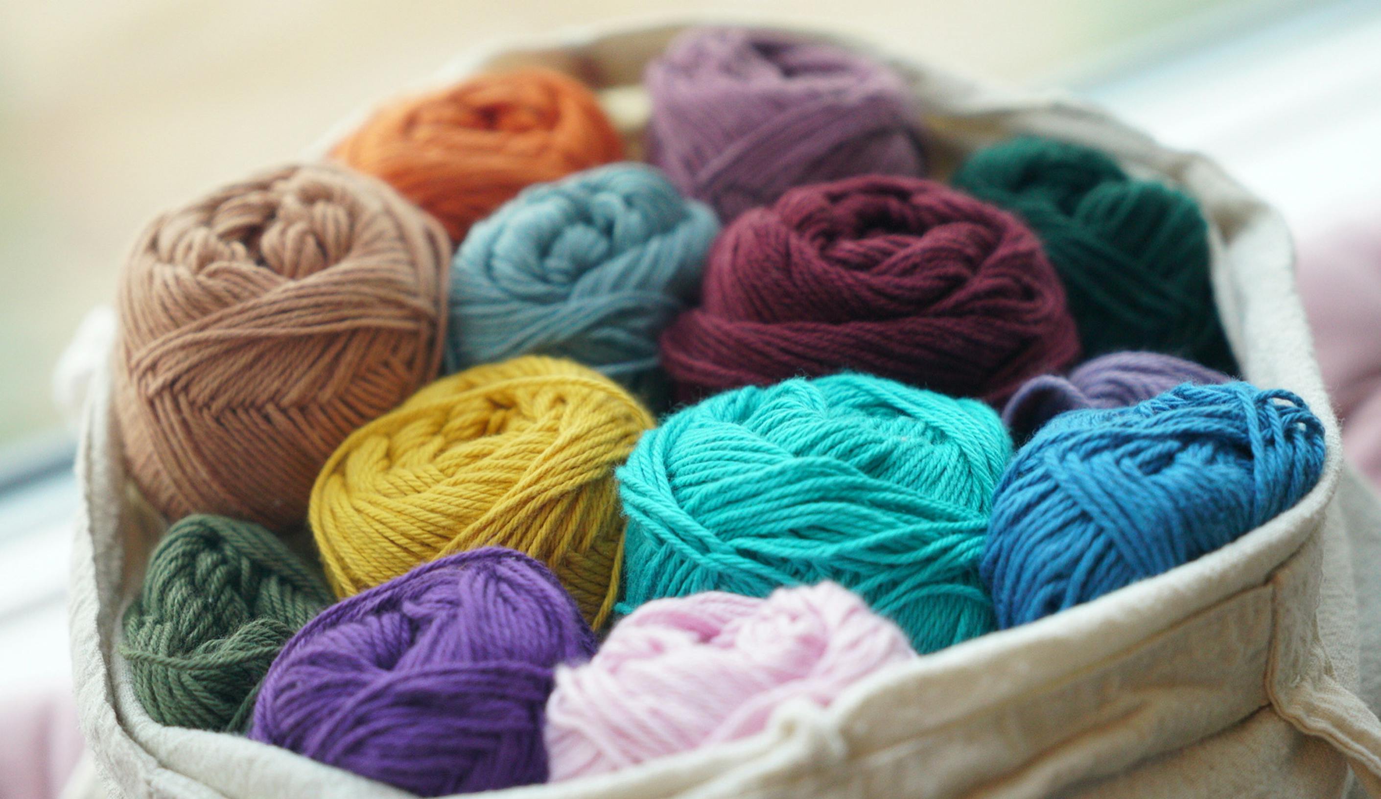 Vibrant collection of yarn balls in a basket, ideal for knitting and crafting projects.