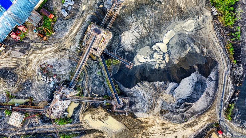 Top-down drone shot of an industrial mining site in Rumpin, West Java, showing machinery and excavation.