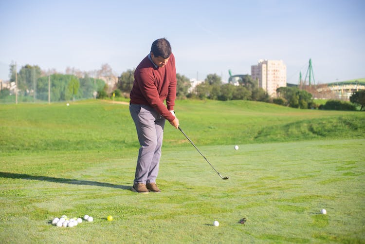 A Man In Red Sweater Standing While Playing Golf