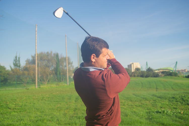 A Man In Red Sweater Holding A Golf Club