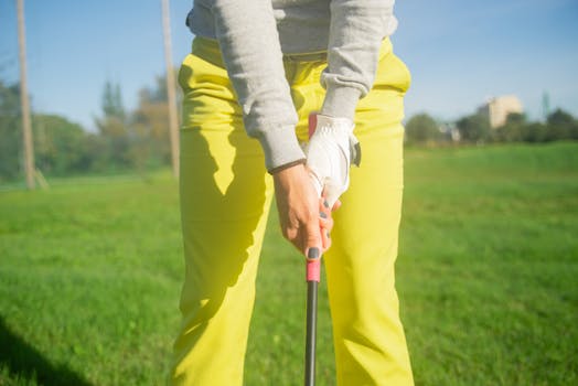 A golfer in yellow pants prepares a swing on a sunny day at a golf course in Portugal.