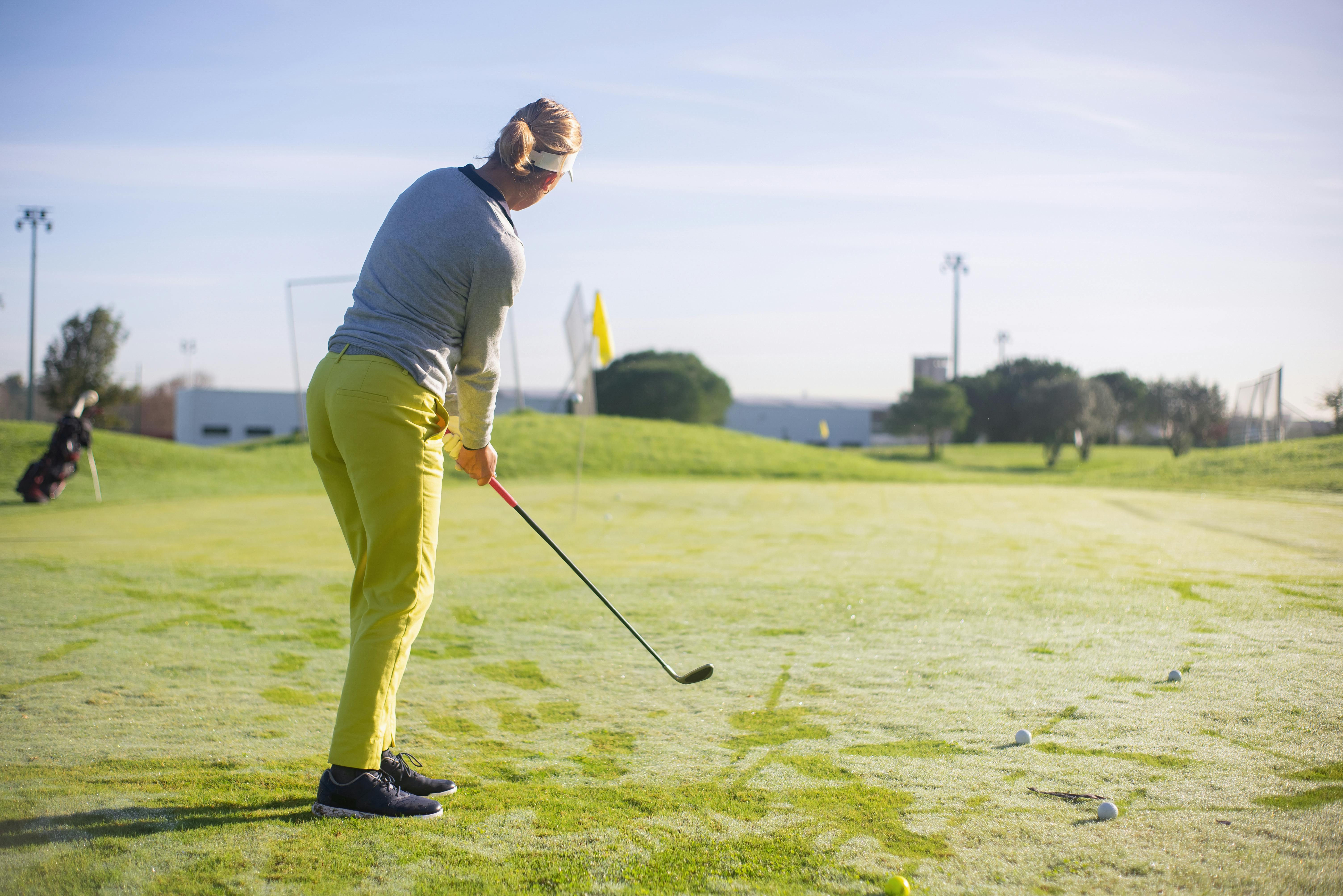 a woman in yellow pants standing while playing golf