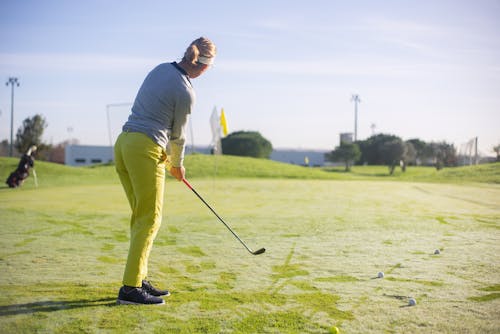 A Woman in Yellow Pants Standing while Playing Golf