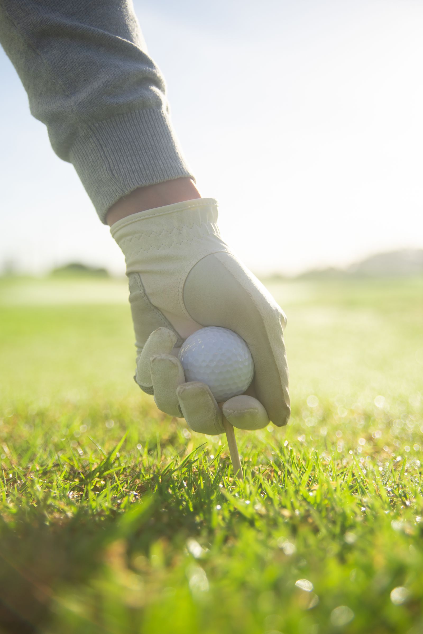 Hand placing a golf ball on a tee