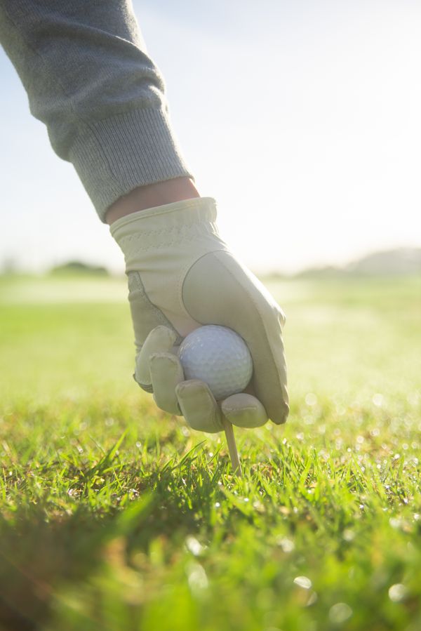 Golf ball balanced on a tee on the green