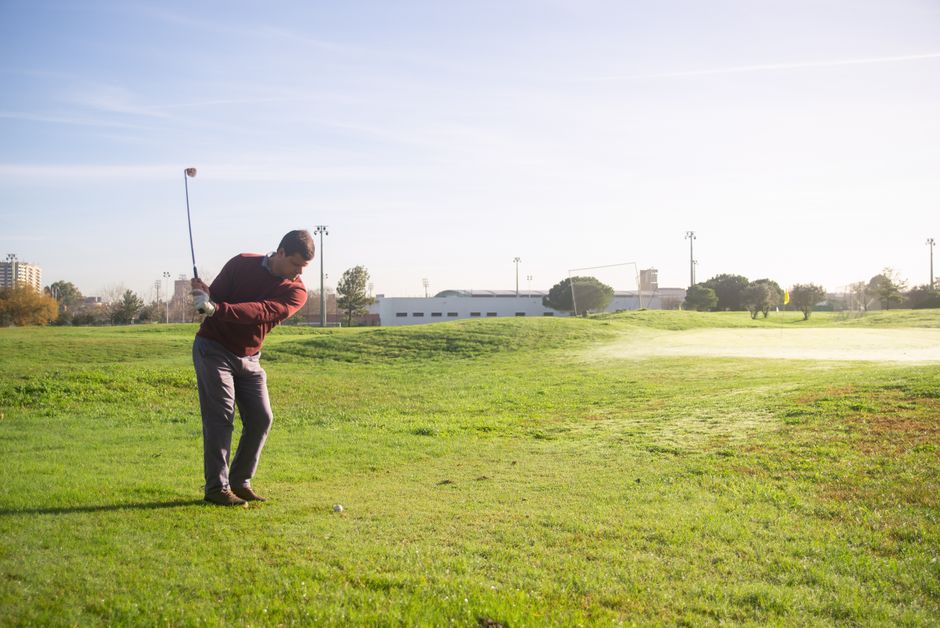 Golfer swinging on a green fairway