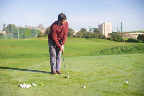 Free A Man in Red Sweater Standing on the Field while Playing Golf Stock Photo
