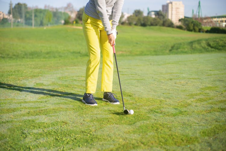 A Person In Yellow Pants Standing While Holding A Golf Club