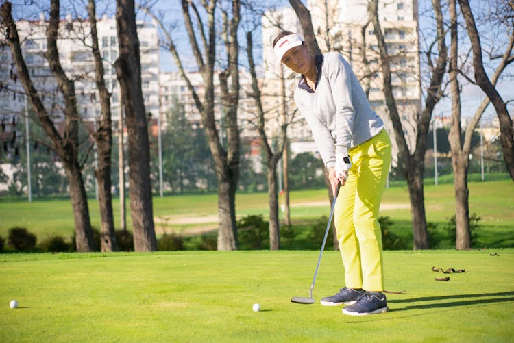 A Woman In Yellow Pants Standing While Playing Golf