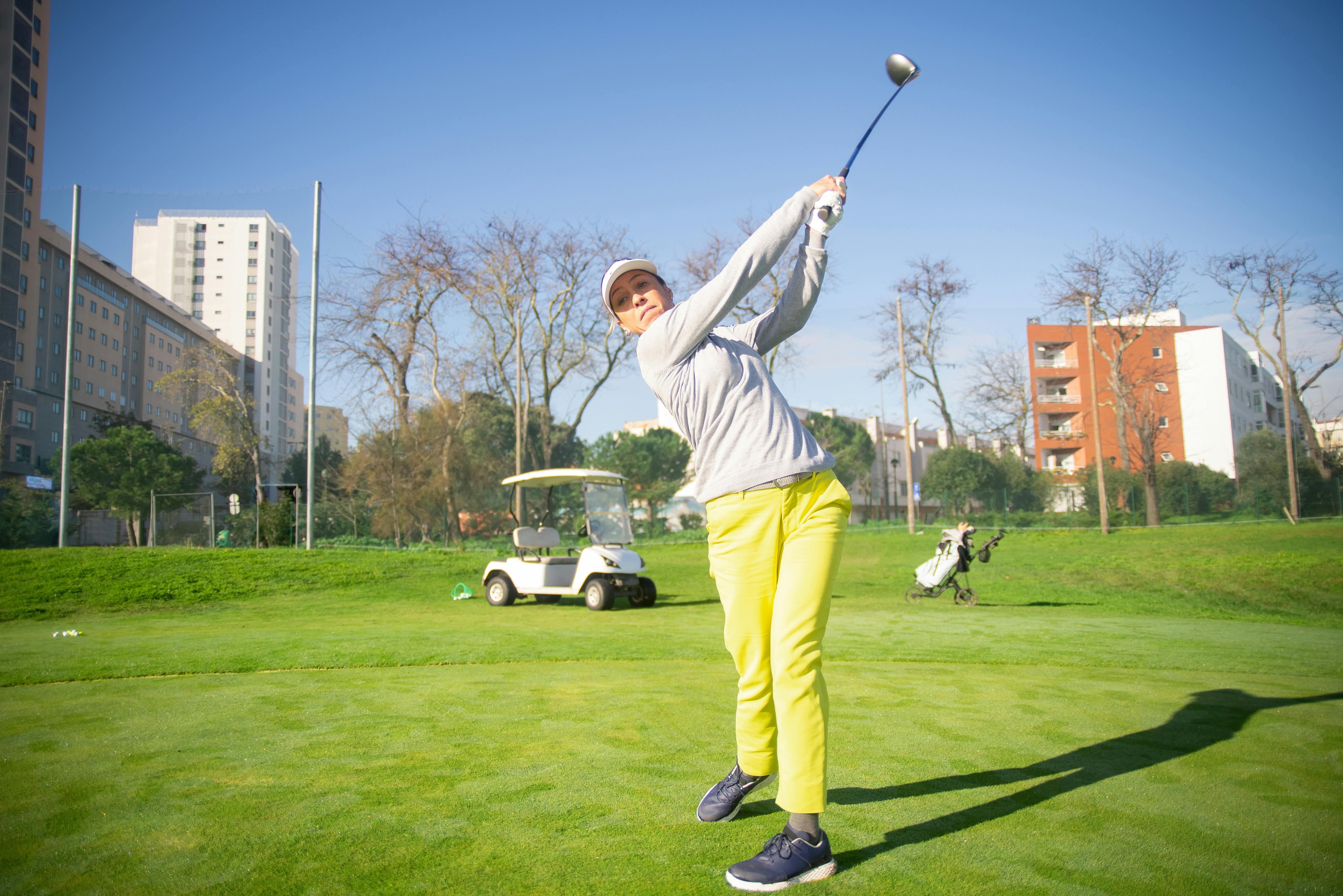 a woman in yellow pants standing while playing golf