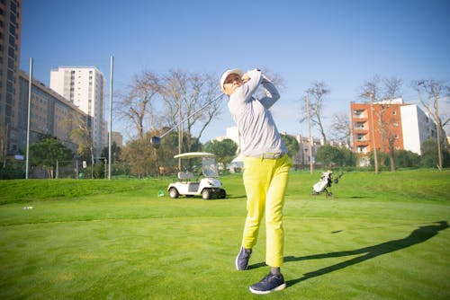 A Woman Standing on Green Grass Field while Playing Golf
