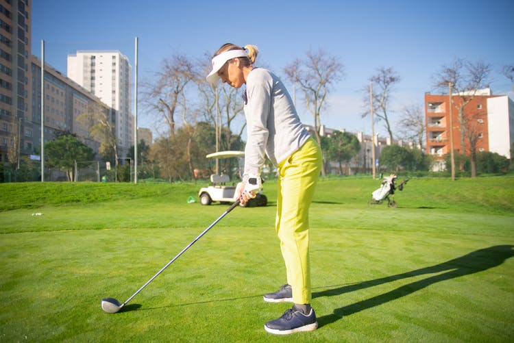 A Side View Of A Woman Standing On The Field While Playing Golf