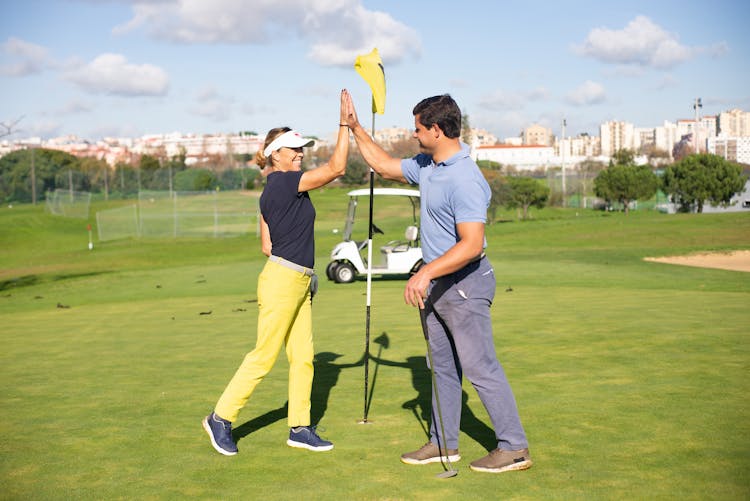 A Man And Woman Doing High Five While Standing On The Field