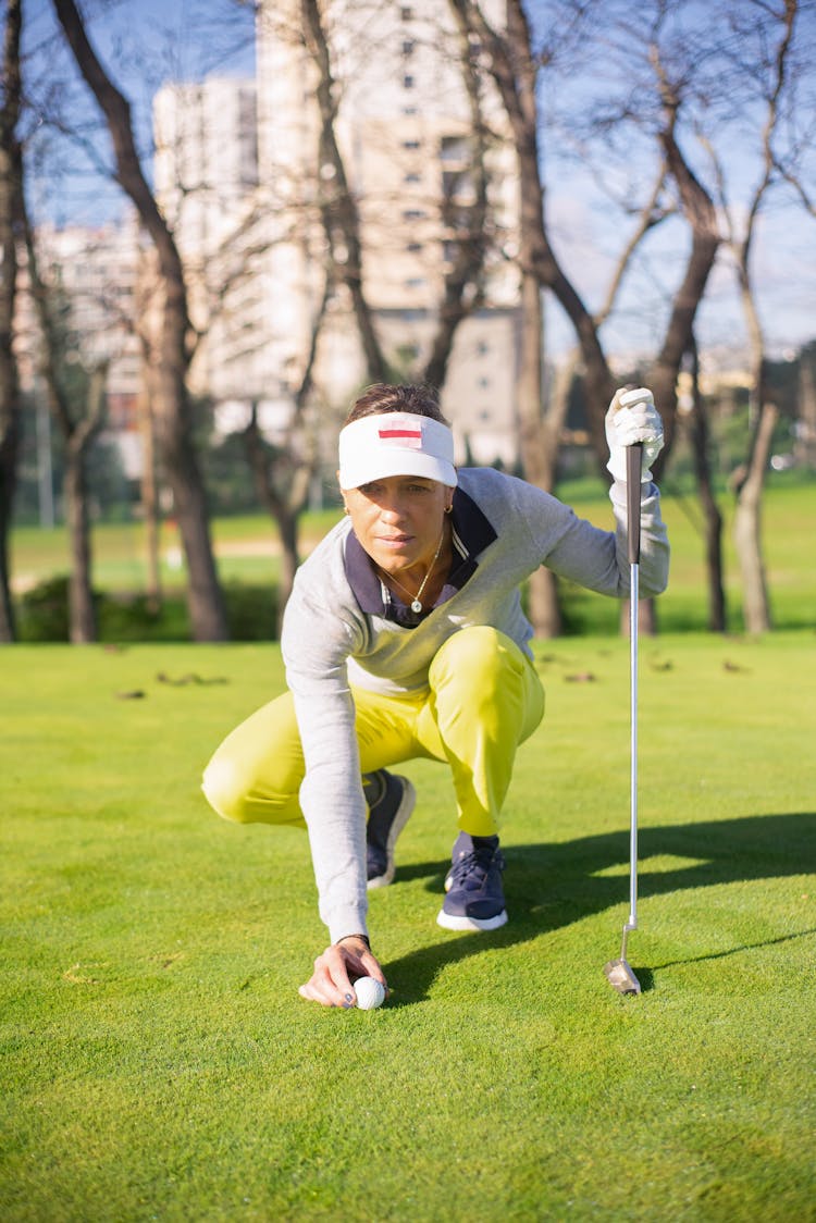 A Woman Wearing Sun Visor While Holding A Golf Club And A Ball