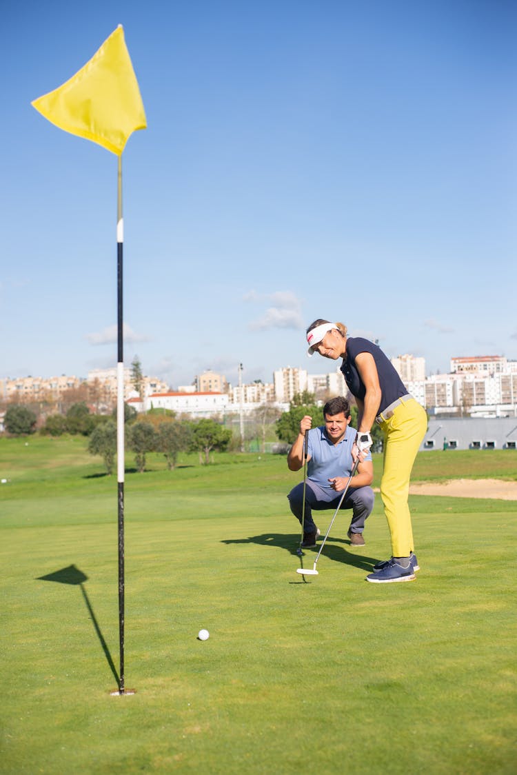 A Woman Playing Golf Near The Man Sitting Beside Her