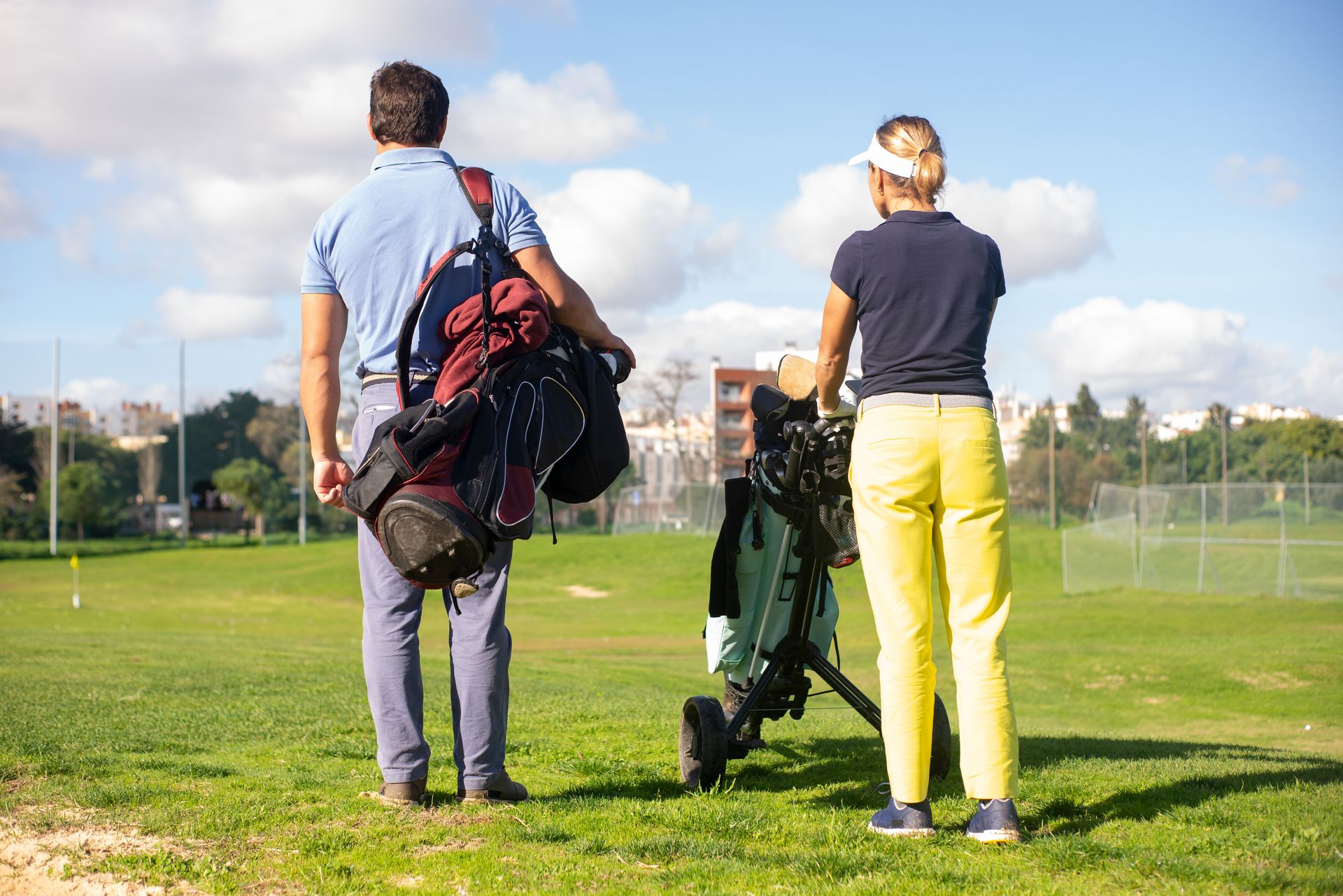 Two golfers walking on a lush golf course in Portugal, carrying clubs under a clear sky.