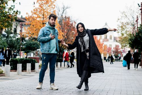 Free Stylish couple holding hands enjoy a lively autumn day on Rasht street, Gilan Province. Stock Photo