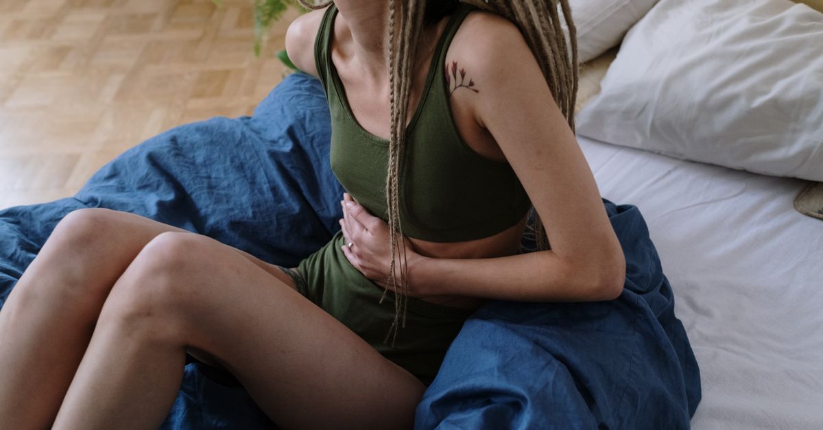 Junge Frau hält sich den Bauch aufgrund von Unterleibsschmerzen