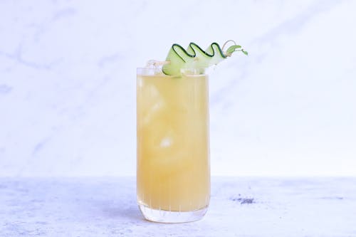 Free Glass of yummy sour ginger lemonade garnished with cucumber slice and served on light marble table in studio Stock Photo