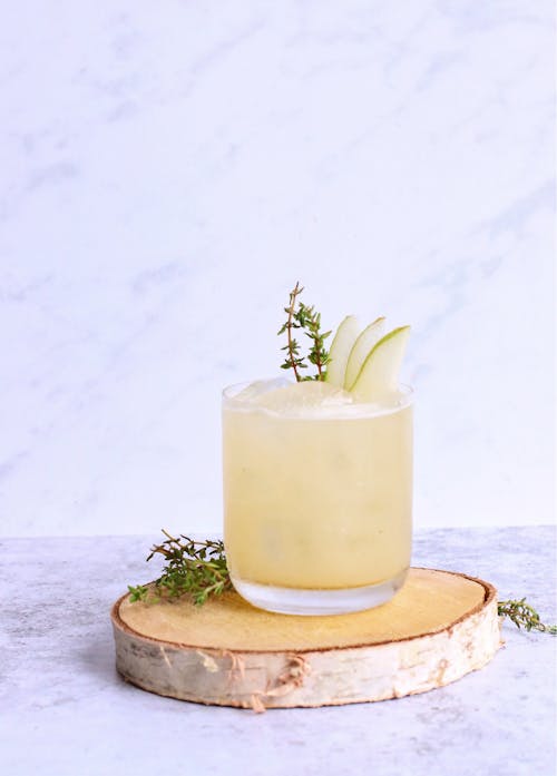 Glass of sweet cold cocktail garnished with pear slices