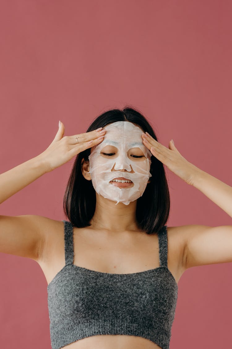 A Woman In Gray Tank Top Touching Her Face With Mask