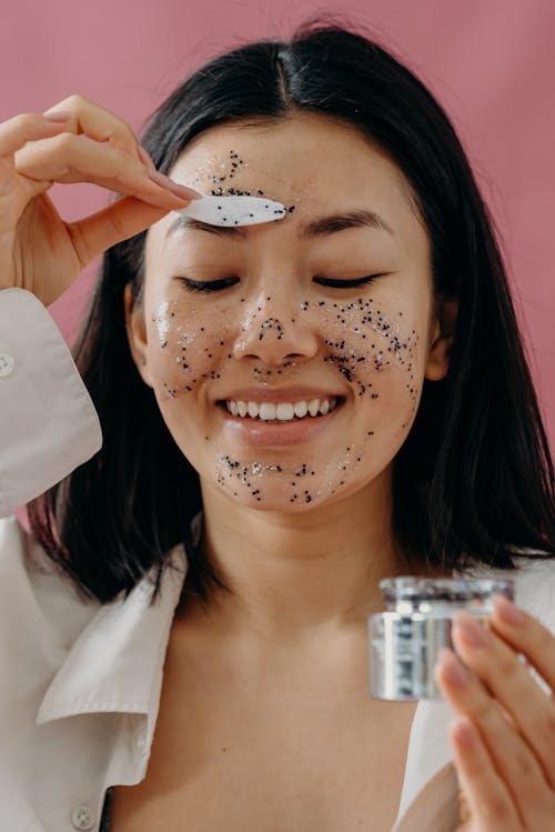 A Woman Applying a Glitter Mask on Her Face Using a Cosmetic Spatula