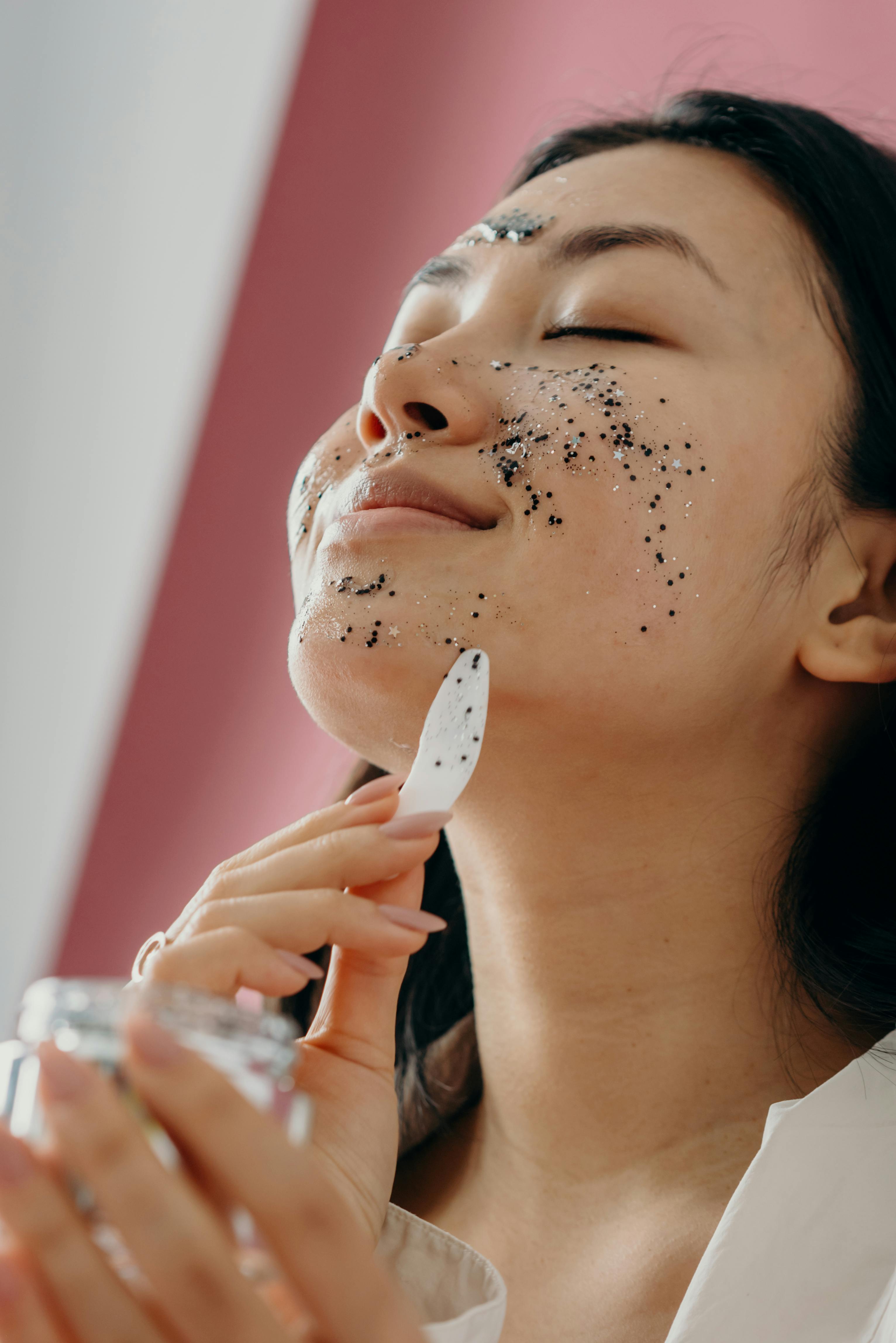 Asian woman enjoying a self-care routine with a glitter face mask. Healthy skin focus.