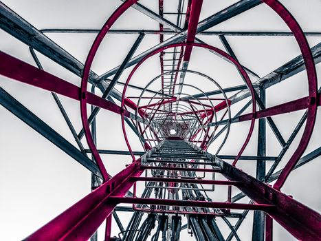 Low angle view inside an industrial tower structure showing its geometric patterns and framework.