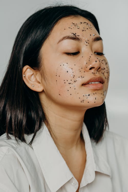 A Woman in White Shirt Looking Down with Glitters on Her Face