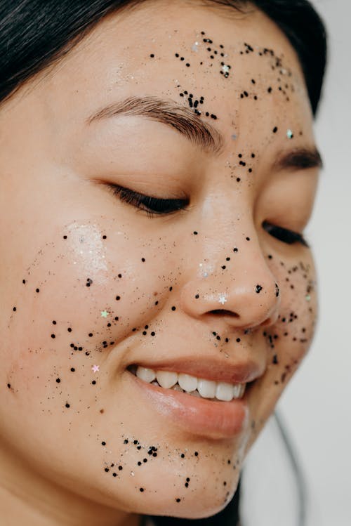 A Close-up Shot of a Smiling Woman with Glitter Mask on Her Face