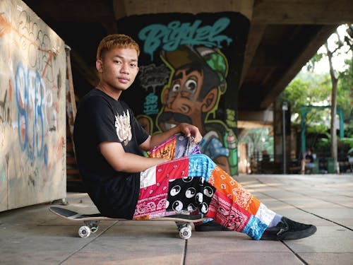 A Man in Black Shirt Sitting on His Skateboard