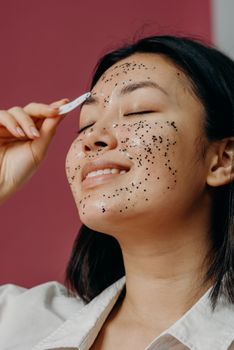 Asian woman enjoying a skincare routine with a glitter mask, promoting beauty and self-care.