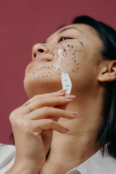 Close-up of a woman applying a glitter exfoliating mask for skincare.