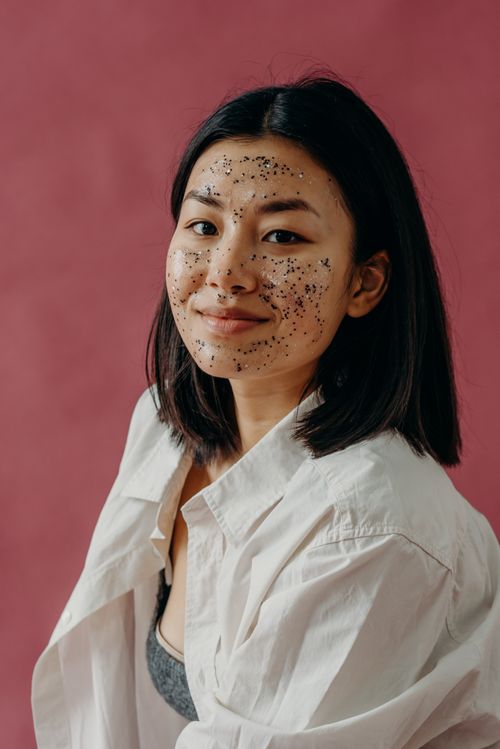 Free A smiling Asian woman wearing a glitter face mask, symbolizing self-care and beauty rituals. Stock Photo
