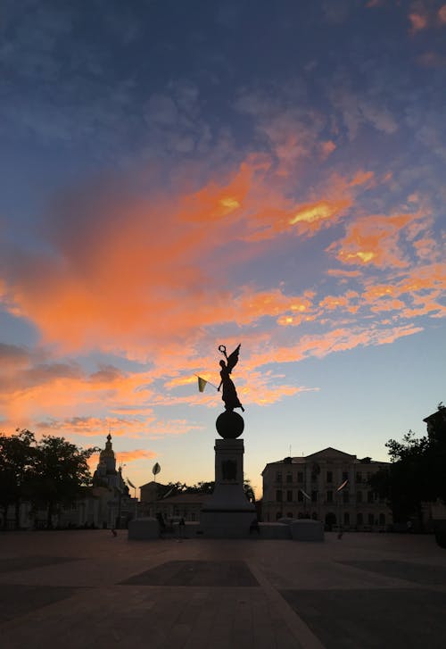 Silhouette of Statue Under Orange Sky