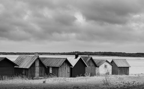 Grayscale Photo of Wooden Houses on the Field